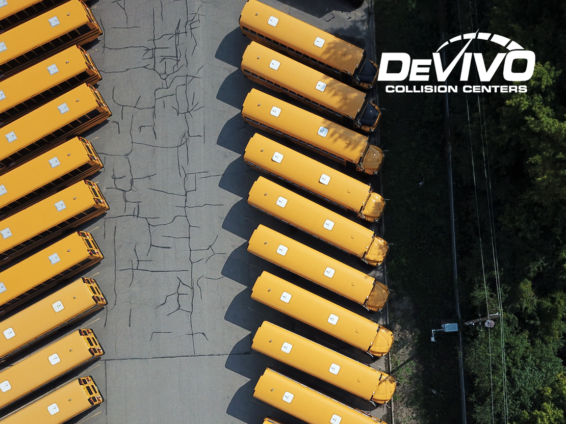 School buses sitting in a bus yard after collision repair and paint work